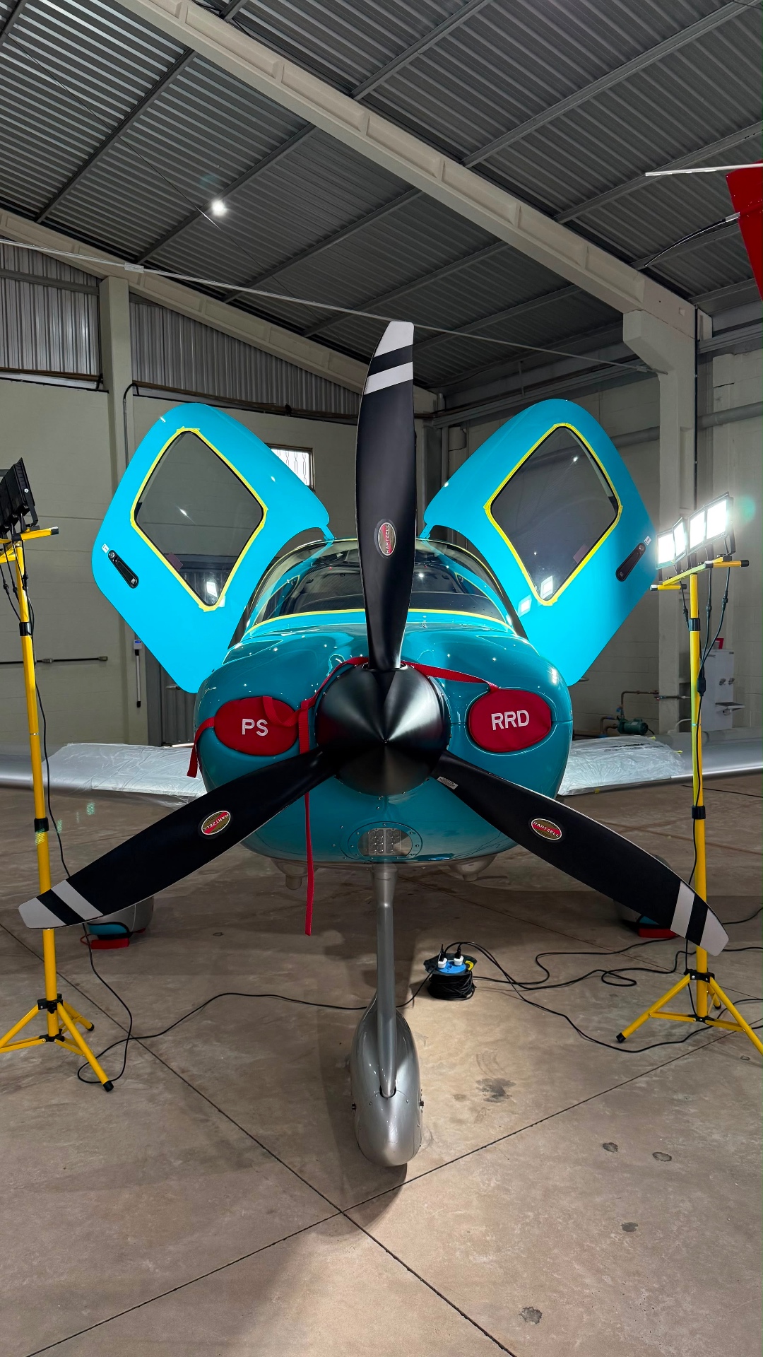 Teal single-engine aircraft with mirror finish under LED light stands