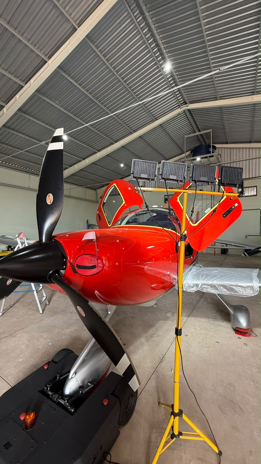 Red single-engine aircraft being polished in the hangar